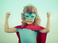 Superhero kid against summer sky background. Girl power and feminism concept